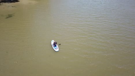 antena de drones sobre una mujer de río tratando de ponerse de pie en una tabla de remo