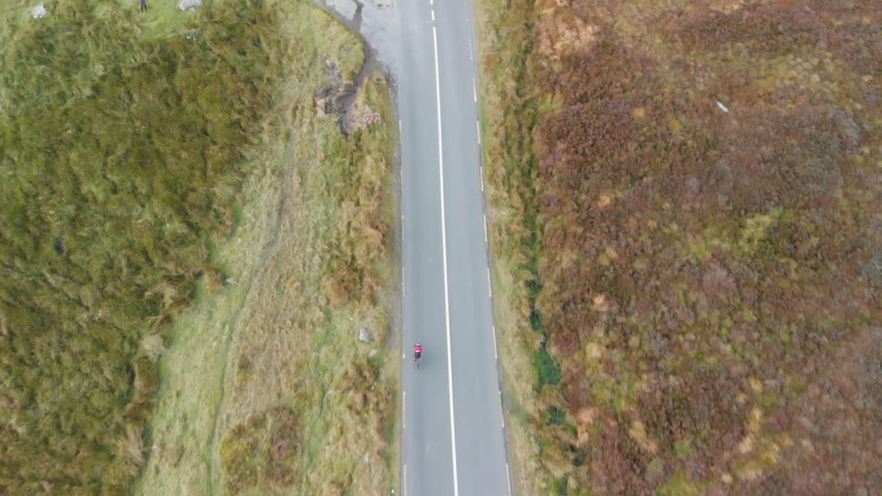 아일랜드의 산을 통과하는 도로에서 자전거 타는 사람을 따라가다