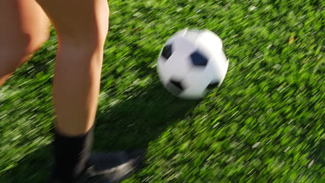 close up on the cleats of a soccer player running with a football dribbling up the grass field to score a goal and win the game