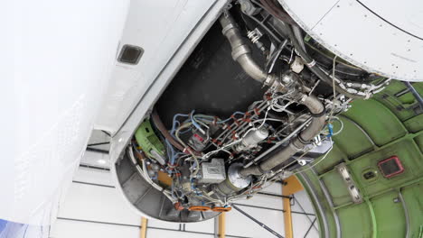 airplane jet engine with open cover in maintenance hangar, tilt up