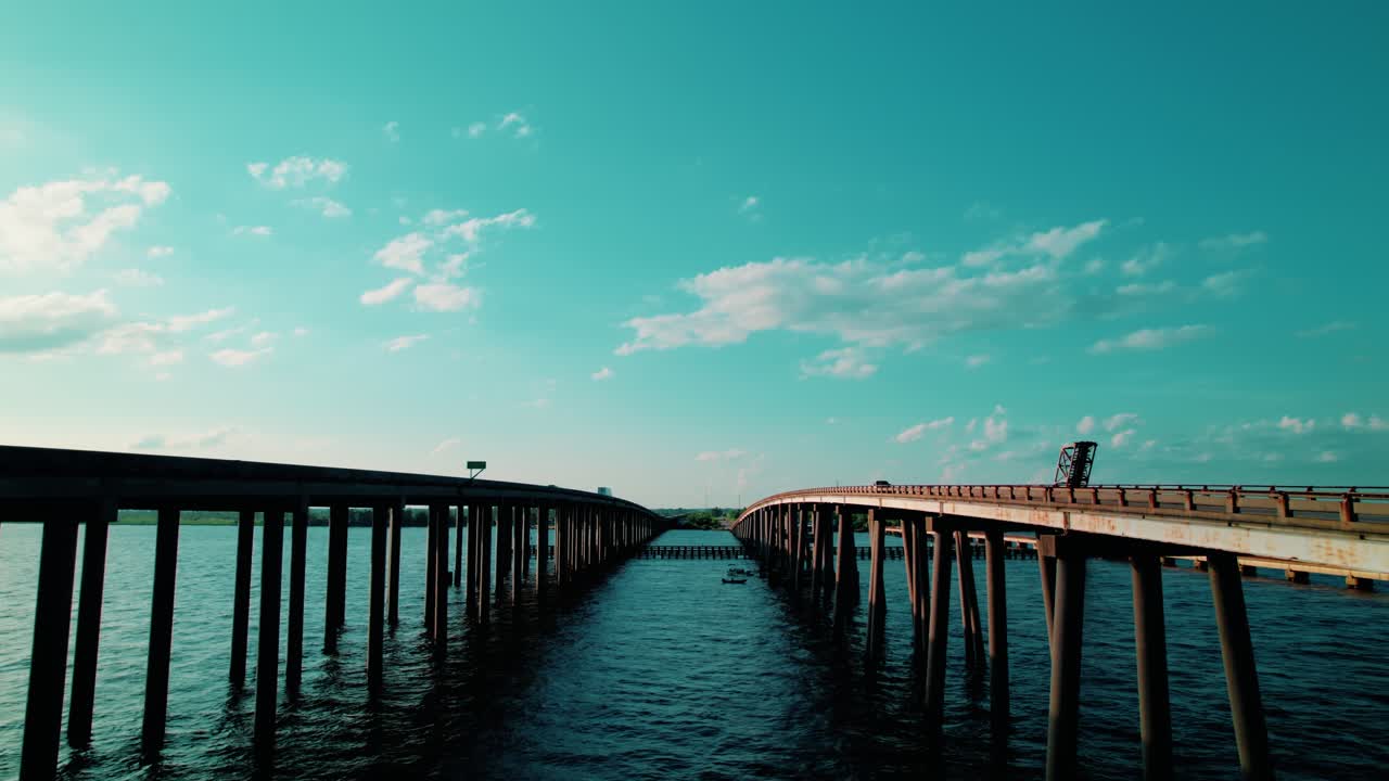 Dramatic low-angle drone reveal showing a semi truck crossing the Manchac Swamp Bridge over bayou waters—ideal for transport and infrastructure content.