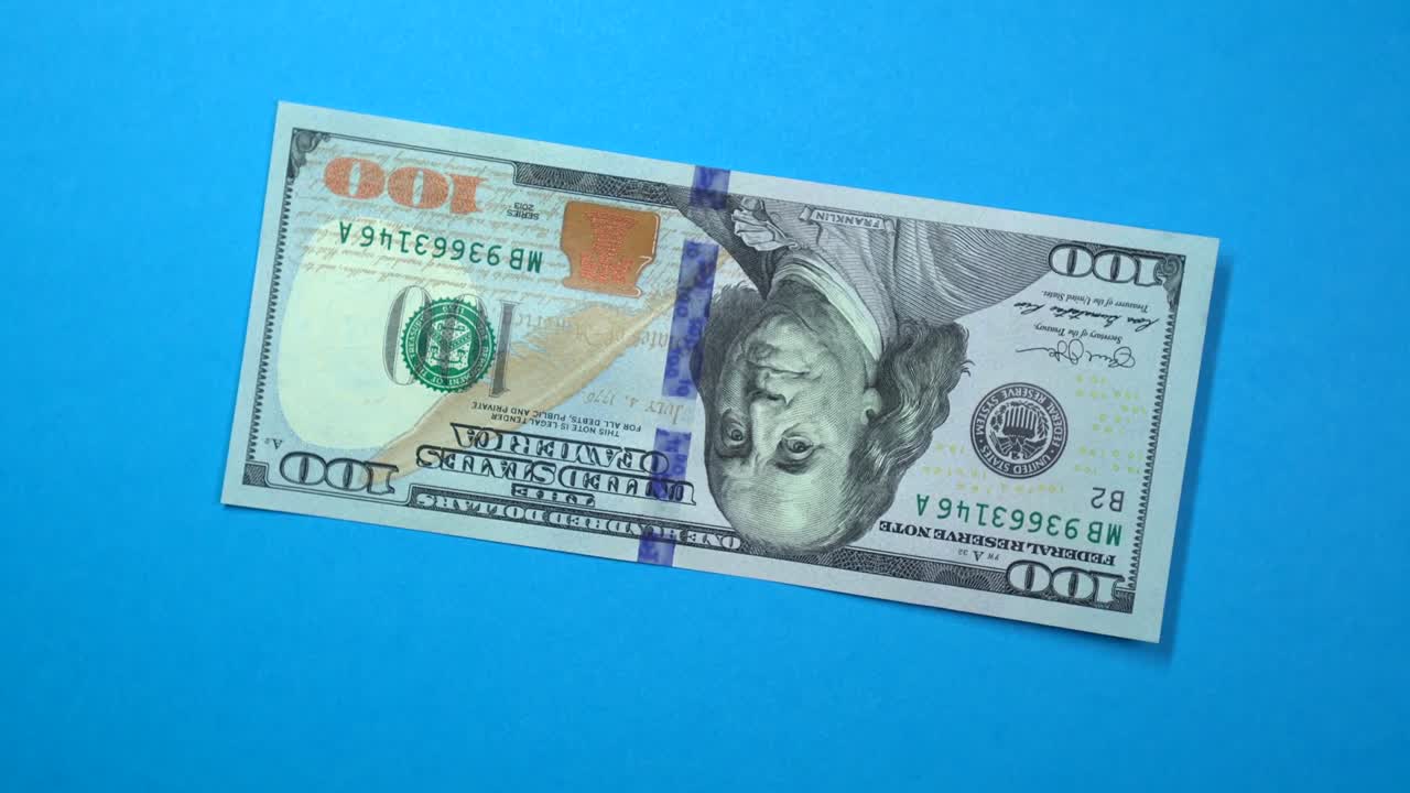 회전하는 파란색 배경에서 빠르게 회전하는 100달러입니다.