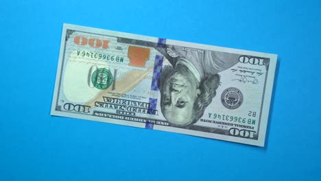 one hundred dollars fast spinning on a rotating blue background.