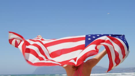 Mujer-Parada-Junto-Al-Mar-Con-Una-Bandera-Americana-Ondeando.-En-La-Playa-4k