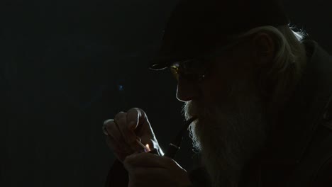 cool mature man silhouette with beard lights pipe: dark room portrait
