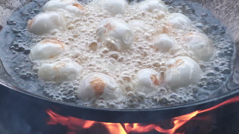 extreme close up boiled duck eggs on frying hot pan, red hot fire