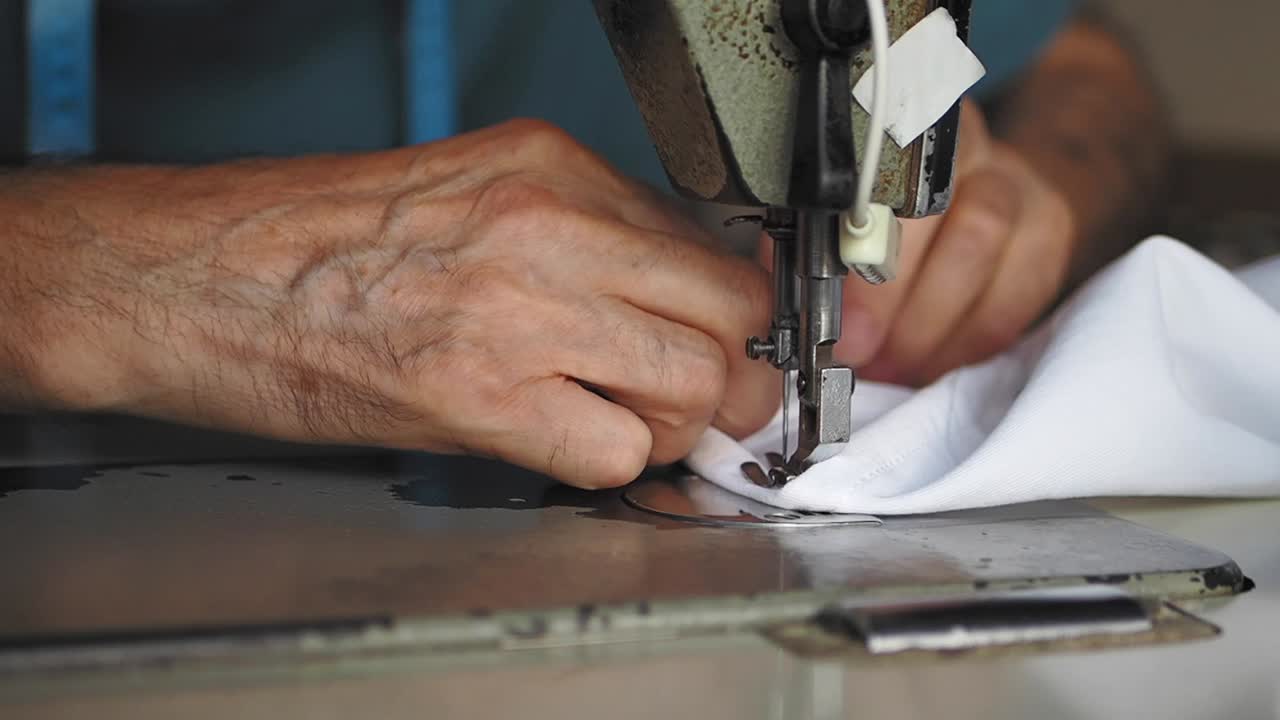 primer plano de un sastre usando una máquina de coser de época