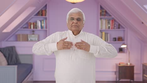 anciano indio haciendo ejercicio de respirar y exhalar