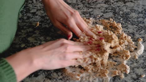 woman hands kneading pieces of dough on floured countertop to join it together