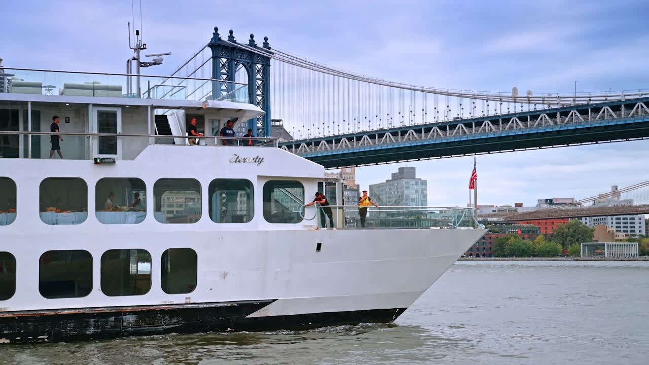 Cruise by manhattan bridge. A boat passes under the Manhattan Bridge as passengers enjoy the view of the city skyline on a cloudy day