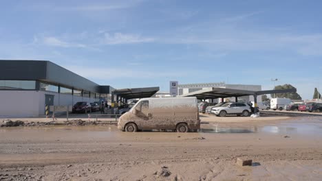 a van covered in mud is parked in a muddy parking lot after the dana storm in valencia