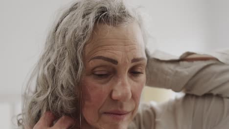 senior caucasian woman moving her long grey hair in bedroom, slow motion