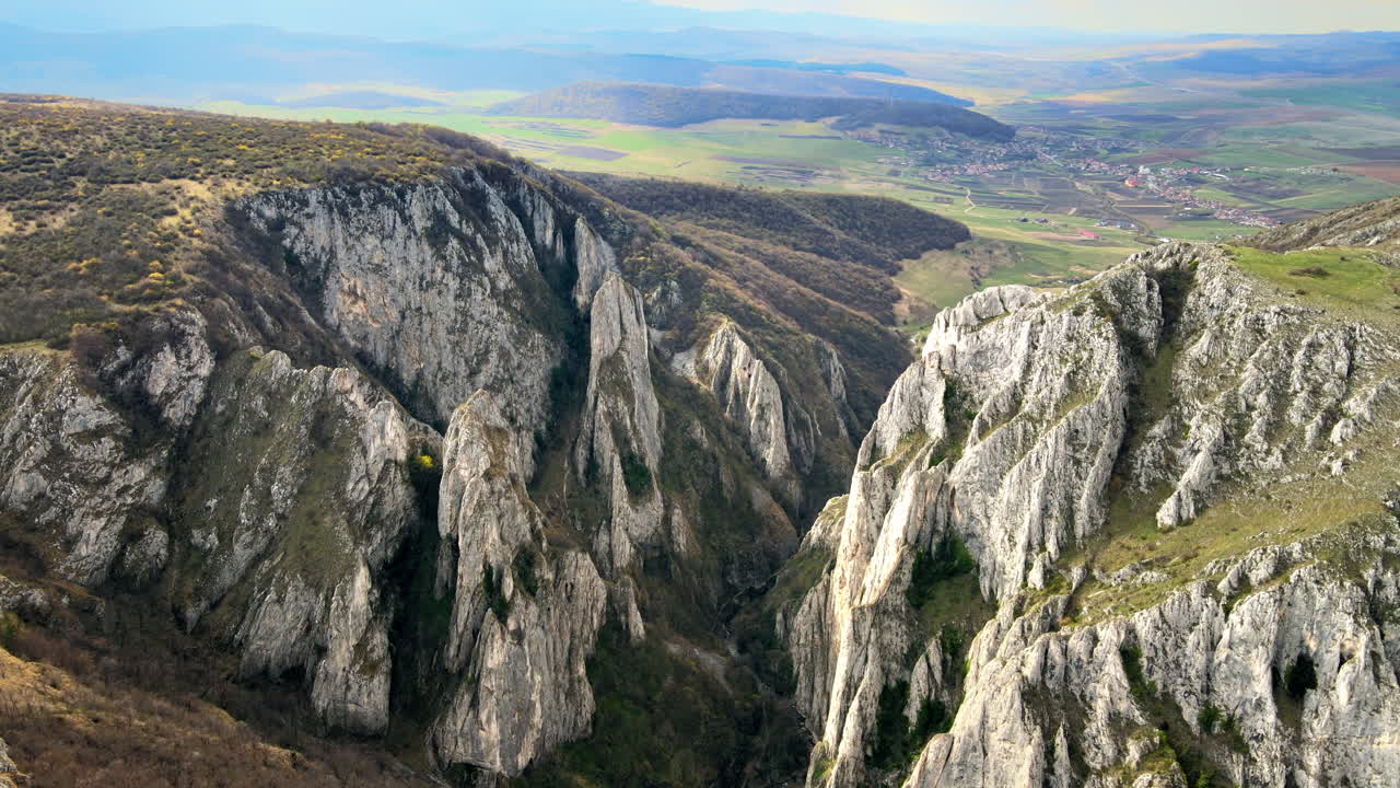 Vista aérea de drone de um cânion rochoso na Romênia. Penhascos rochosos com vegetação esparsa. Campos ao longe.