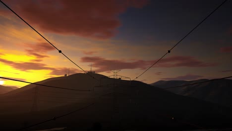 the high voltage electricity tower on mountains at sunset. 4k time lapse of sunset with transmission electricity steel pylon tower, electricity pylons in the countryside