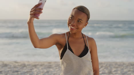 Retrato-De-Una-Atractiva-Mujer-Afroamericana-Usando-Un-Teléfono-Inteligente-Tomando-Una-Foto-Selfie-En-La-Playa-De-Verano-Disfrutando-De-Unas-Vacaciones-Relajadas