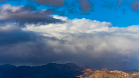 a huge storm front moves in over the rugged peaks in the mojave desert bringing rain and sleet in the winter - time lapse