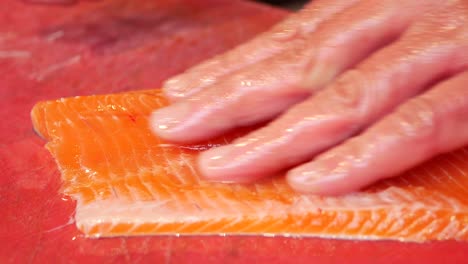 close-up of raw salmon fillet being prepared for sushi