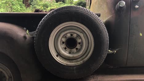 a shot of the spare tire on a rusted out car parked on the side of the street