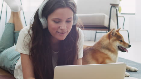 mujer joven que trabaja en su computadora portátil en casa junto a su perro 7