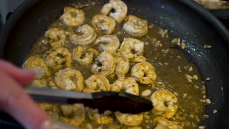 sauteing shrimp in butter and herbs in a frying pan on the stove - shrimp and grits meal