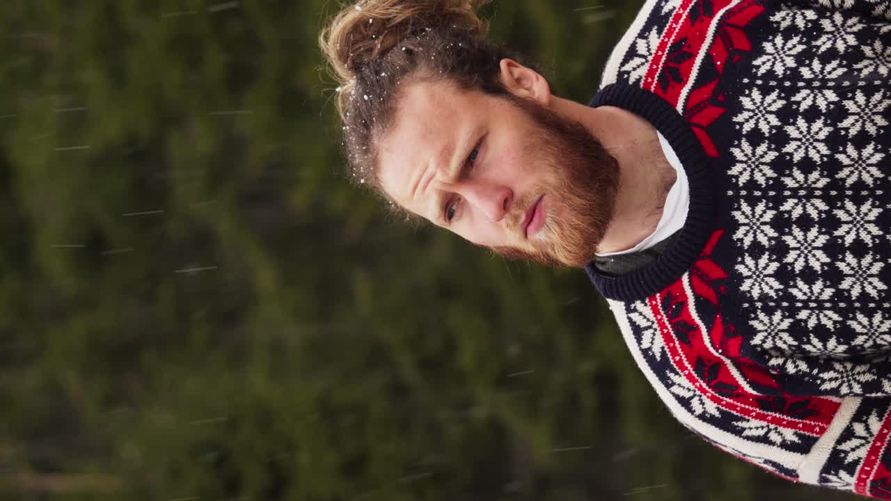 - вертикальный задумчивый человек смотрит в камеру, стоя под снегопадом