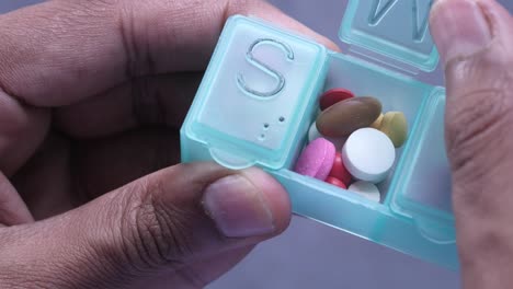 person holding a pill organizer with medications