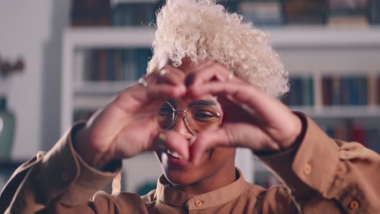 Donna afroamericana mostra il gesto del cuore con le dita, simbolo d'amore.