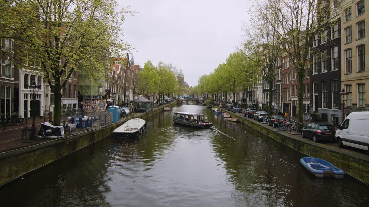 canal de amsterdam de la ciudad vieja en un día nublado de primavera con botes de atraque, tiro estático amplio, holanda