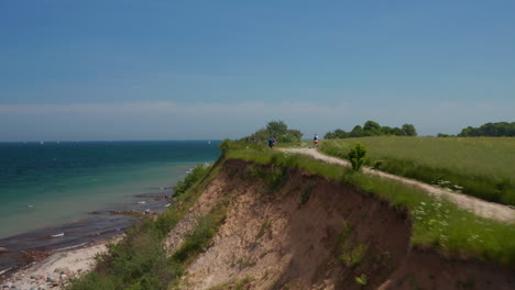 Friedliche-Küstenlandschaft,-Luftdrohne,-Die-über-Fußweg-Fliegt,-Mit-Blauem-Türkisfarbenem-Ostseewasser-Im-Hintergrund,-Vorwärts,-Tag