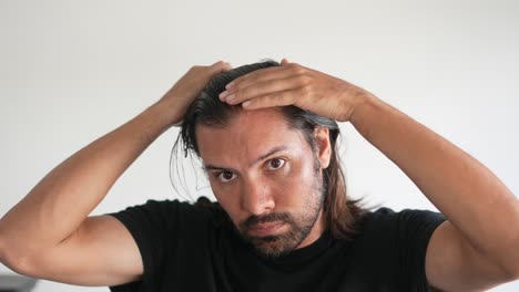 Latino-Mann-überprüft-Sein-Haar-Mit-Zurückweichendem-Haaransatz-Und-Glatze,-Alopezie