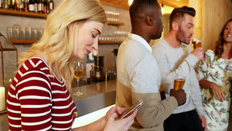 Young-woman-using-mobile-phone-while-friends-are-having-drink-4K-4k