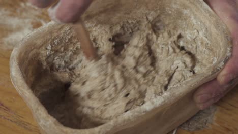 mixing bread dough mixture in a container with a wooden spoon - close up slowmo