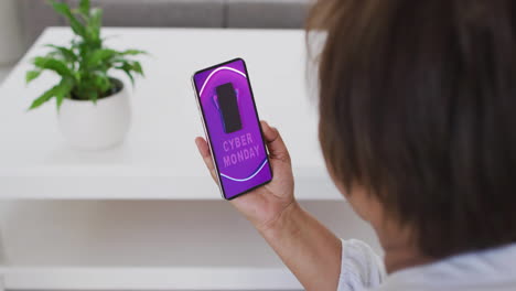mujer biracial usando teléfono inteligente en casa compras en línea en el día de venta del lunes cibernético, cámara lenta