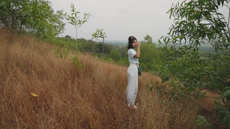 Cinematic-shot-of-Girl-tourist-with-umbrella-at-rural-mountain-in-bushes