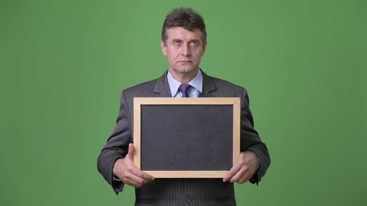 Mature handsome businessman against green background