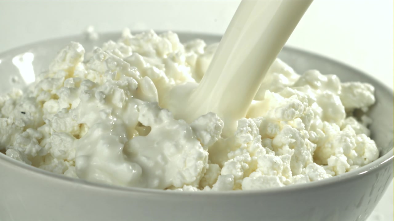 Latte versato su ricotta fresca in una ciotola bianca