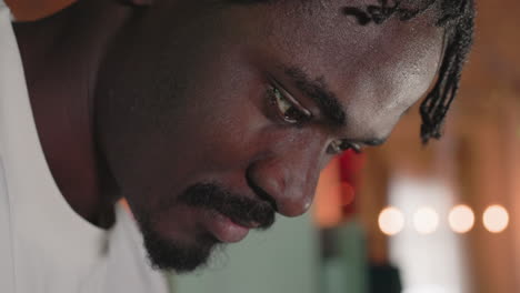close-up shot of a man concentrating on a task, with his face in profile. his eyes are focused and his expression suggests deep thought or attention. the background features soft bokeh lighting