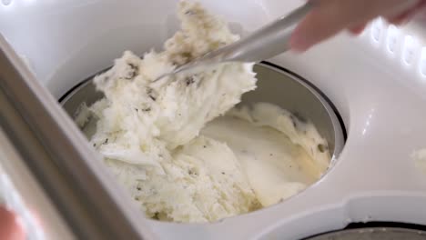 hand mixing vanilla chocolate chip ice cream in display freezer, closeup