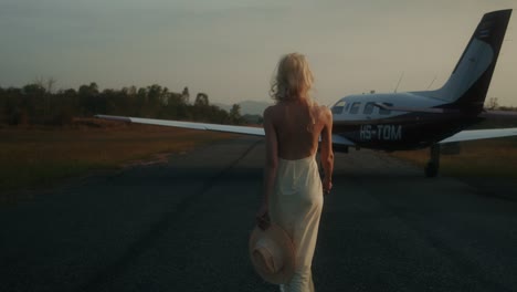 woman walking to airplane at sunset