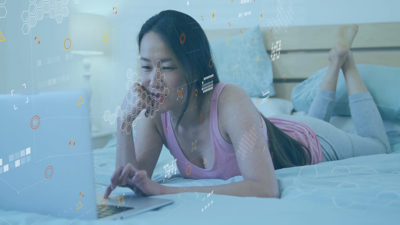 Mid adult woman tapping laptop trackpad on bed, generating dense tech overlay while analyzing data
