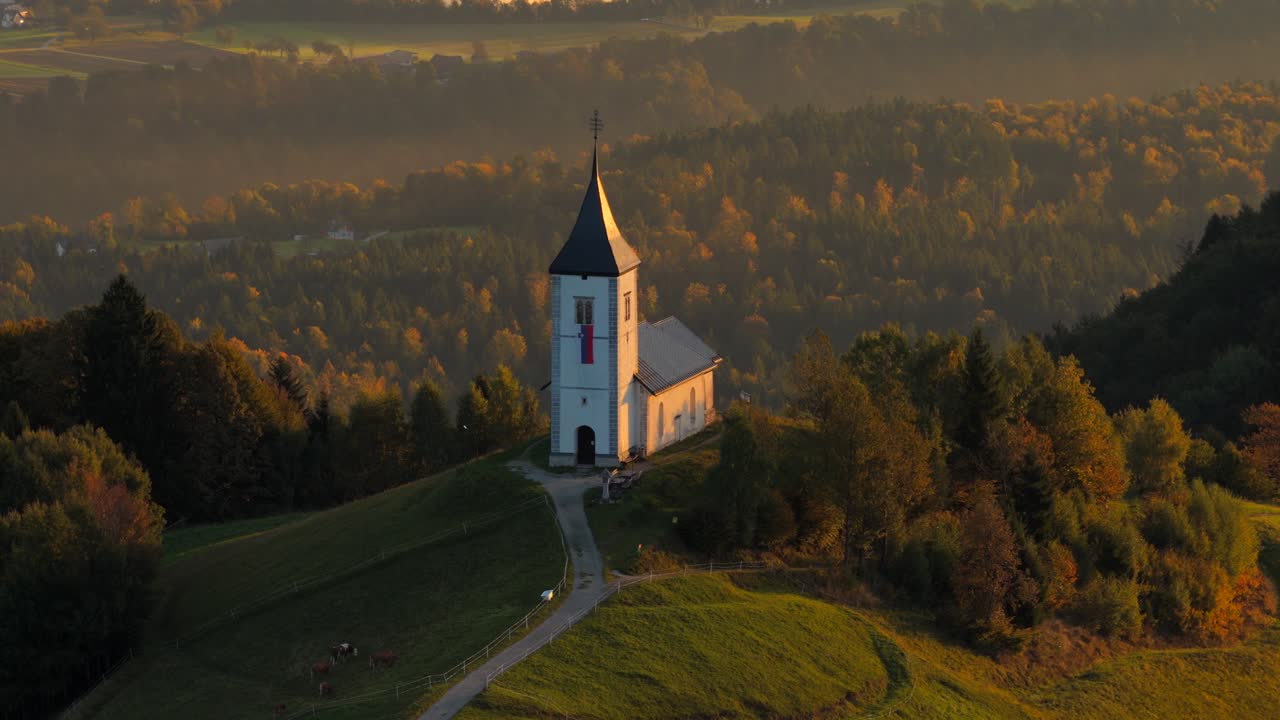 Aerial rising shot of Jamnik church with valley in background, Church of St. Primus and Felician. Foggy morning in Slovenia. Calm and peaceful scene