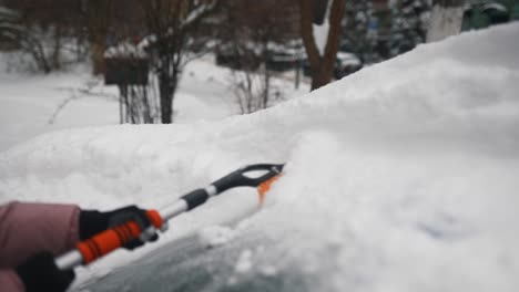 quitando la nieve del parabrisas de un coche en un día de nieve