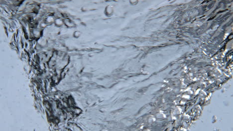 sparkling tonic moving inside glassware closeup. clean liquid swirling vessel