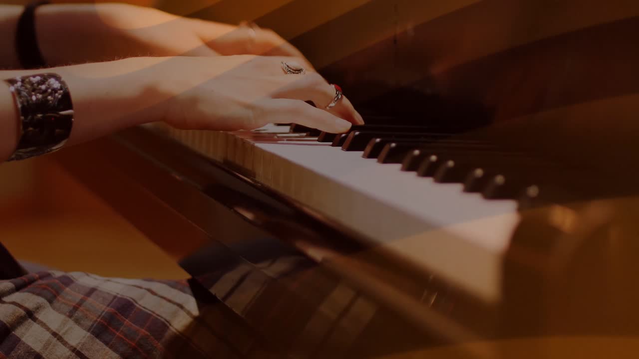 Pianist's hands hovering over piano keys pressing chords making music under orange flares