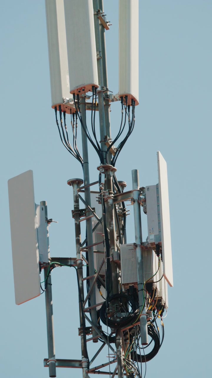 Close up of a telecommunications antenna mounted on a metal tower structure against a clear blue sky