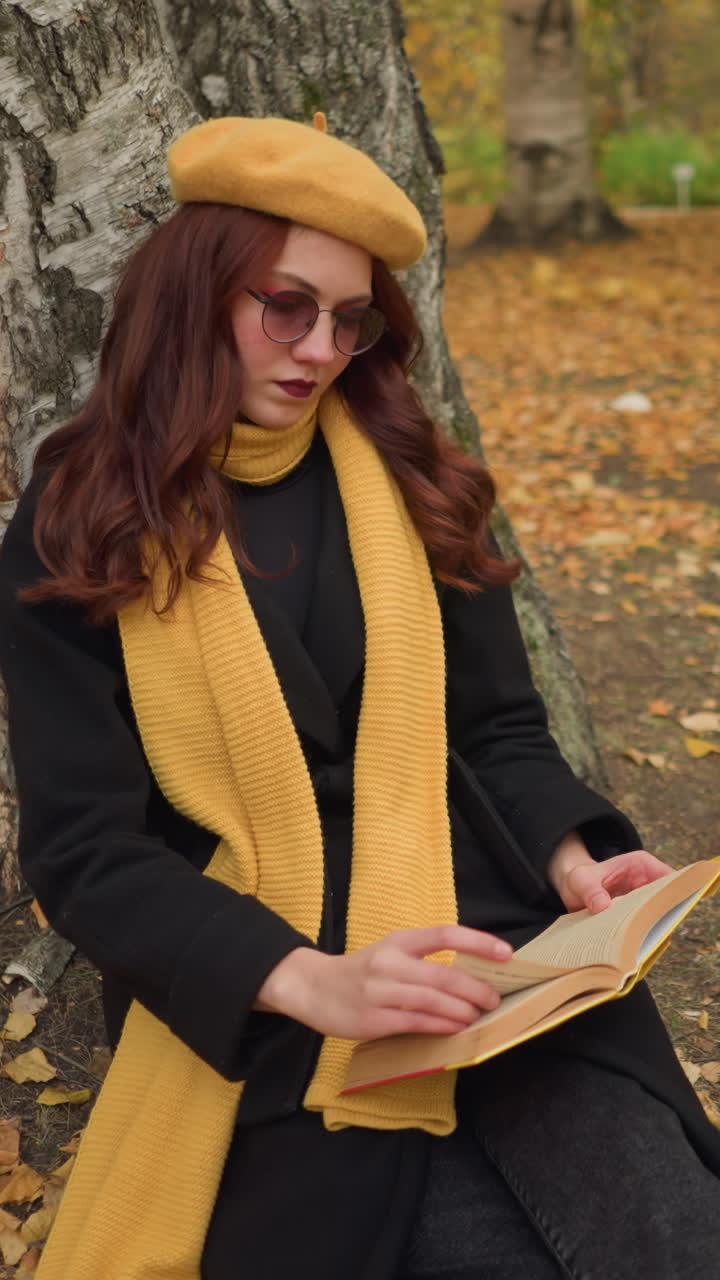 el turista en la soledad hojea las páginas del libro contemplativamente, sentado solo en la naturaleza, vestido con boina amarilla y silenciador, rodeado de hojas de otoño, inmerso en un momento de lectura pacífica