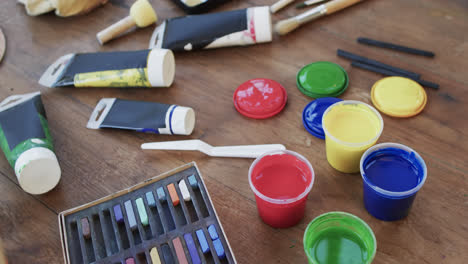 close up of paints and brushes on table in studio, slow motion