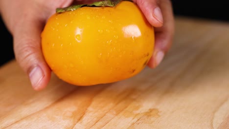 hands gently handle a ripe persimmon