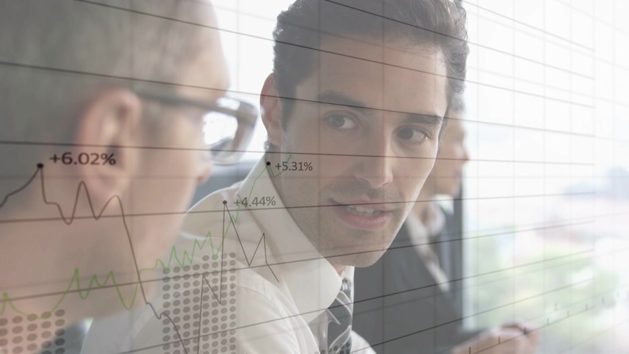 Two execs reviewing funds at table by window, right exec speaking gesturing causing charts updating