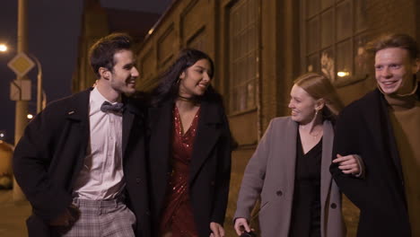 two couples of friends dressed in elegant clothes walking in the street while talking and laughing after new year's party